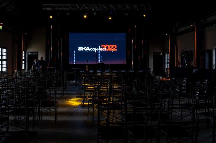 Imagem do palco do SKA Connect 2022. Em primeiro plano, as cerca de 300 cadeiras para os participantes. Ao fundo, o telão de LED em que ocorrerão as apresetações.